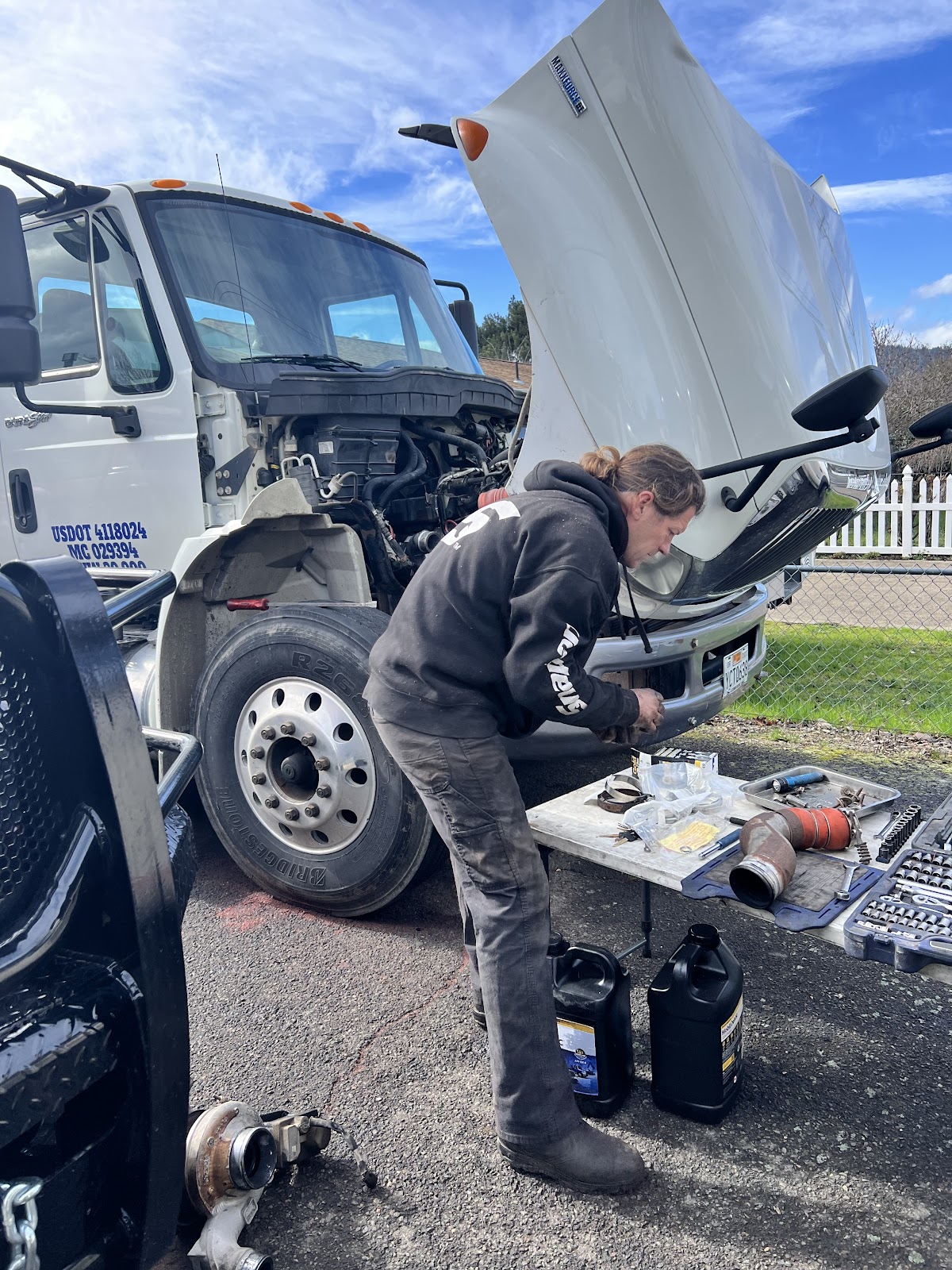 Steve working under the hood of a commercial truck, tools laid out